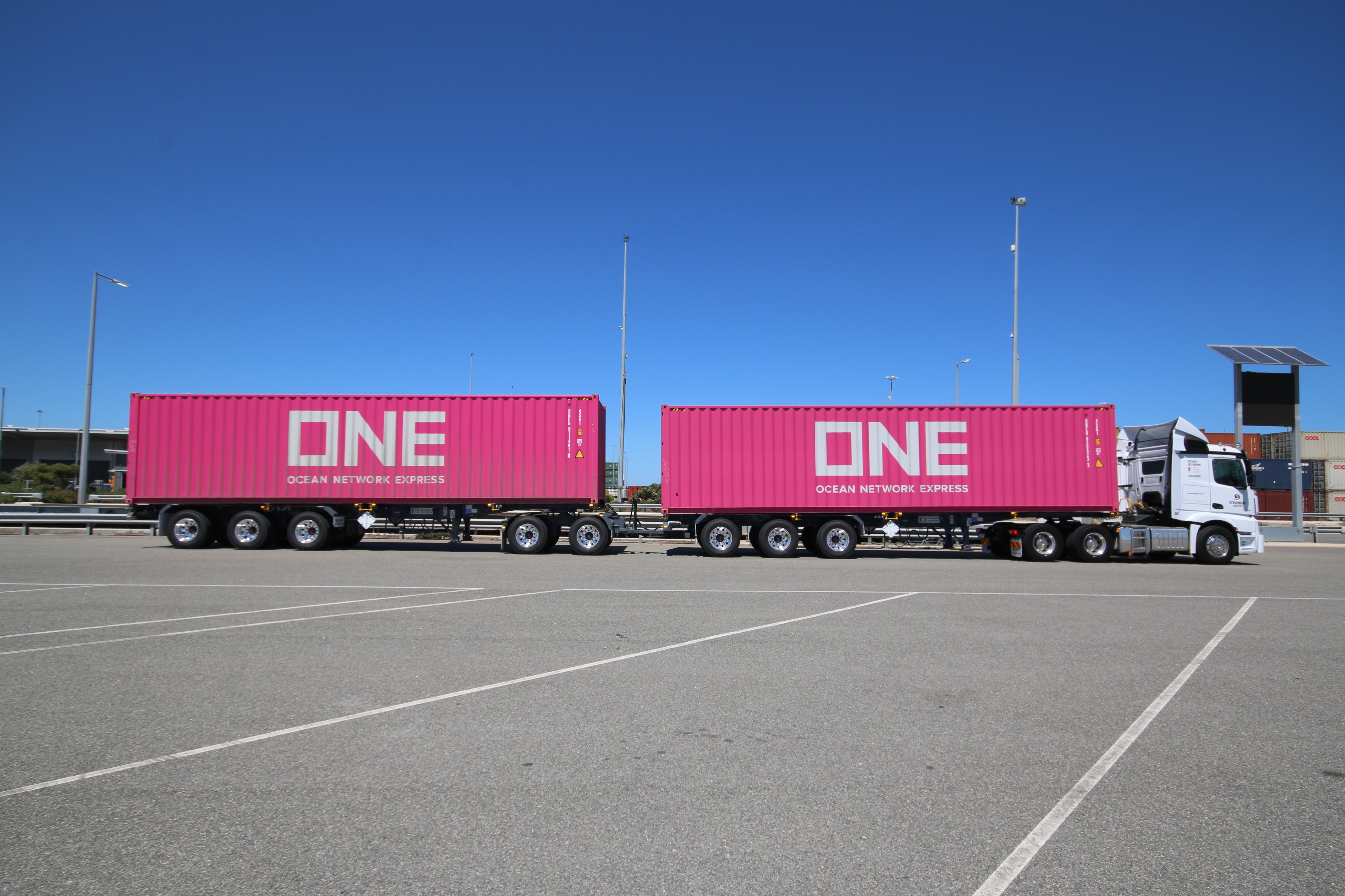 Road Train with two trailers with pink shipping containers parked in a carpark
