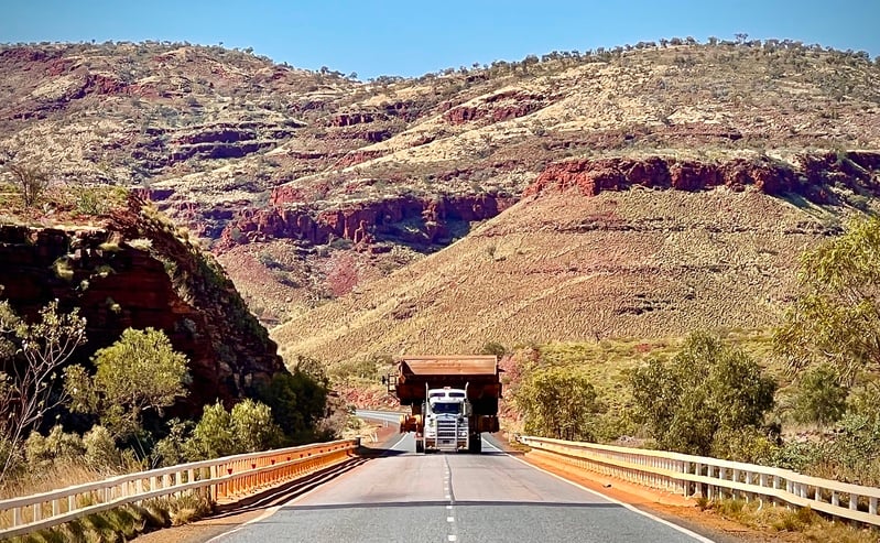 truck with oversize overmass load crossing a bridge on a regional road with hills in the background